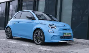 Niebieski Abarth 500e, gotowy do testu, zaparkowany przed nowoczesnym budynkiem.