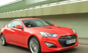 Czerwony Hyundai Genesis Coupe 3.8 V6 pędzi pod zielonym wiaduktem.