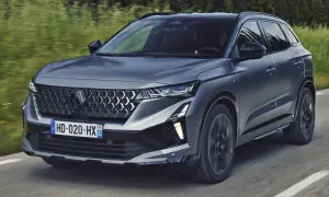 Nowy Renault Austral 2025 w ciemnoszarym kolorze pędzi po drodze, otoczony zielenią.