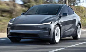 Szary Tesla SUV pędzi po drodze, otoczony rozmytym krajobrazem.