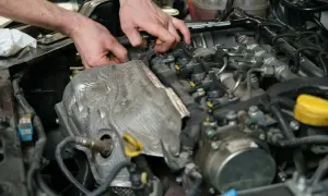 Mechanik pracuje przy silniku, wymieniając czujnik położenia wałka rozrządu.
