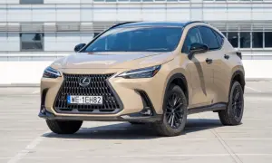 Elegancki, beżowy Lexus 350h z czarnym dachem i felgami stoi na parkingu przed nowoczesnym budynkiem.