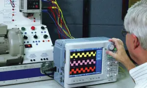 Mężczyzna reguluje oscyloskop, który pokazuje przebiegi, pomagając zrozumieć, jak zmierzyć moc silnika elektrycznego.