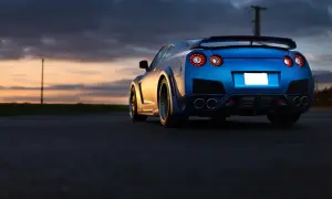 Niebieski Nissan GTR z charakterystycznymi światłami z tyłu, zaparkowany o zachodzie słońca. Zastanawiasz się nad nissan gtr cena?