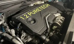 Silnik 1.2 PureTech, często chwalony w opiniach za oszczędność. Widok z bliska na pokrywę silnika z żółtym napisem.