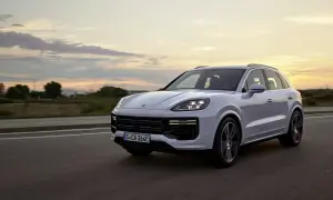 Biały Porsche Cayenne Turbo sunie po drodze o zachodzie słońca, z chmurami malującymi niebo.