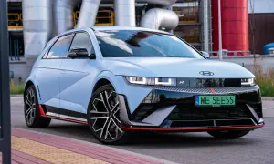 Niebieski Hyundai Ioniq 5 N z czerwonymi akcentami stoi przed przemysłowym budynkiem z rurami.