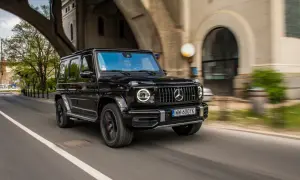 Czarny G-wagon pędzi pod wiaduktem, kierowca w okularach obserwuje drogę.