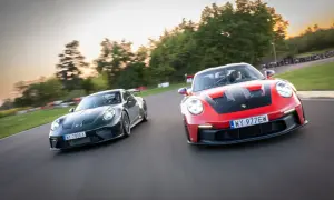 Dwa Porsche GT3, czerwone i zielone, ścigają się na torze wyścigowym.