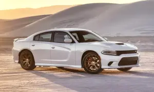 Biały Dodge Charger SRT z brązowymi felgami na pustyni o zachodzie słońca.