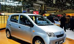 Srebrny Daihatsu Cuore na targach motoryzacyjnych, wśród tłumu ludzi i innych stoisk.