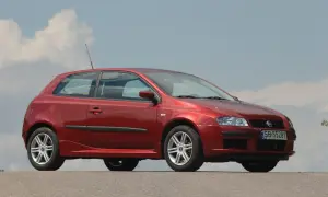 Czerwony Fiat Stilo 1.9 JTD z felgami aluminiowymi stoi na tle błękitnego nieba z chmurami.