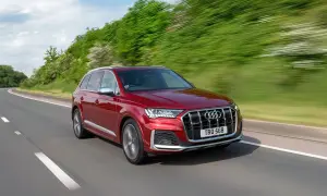 Czerwony Audi SQ7 pędzi po krętej drodze, otoczony zielenią.