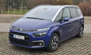Niebieski Citroen C4 Spacetourer zaparkowany na betonowej nawierzchni z trawą.