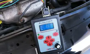 Tester diagnostyczny mierzy moc alternatora samochodowego, pokazując napięcie i inne parametry.