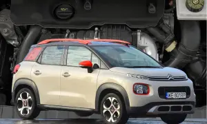 Nowy Citroen C3 2025 w beżowym kolorze z czerwonymi akcentami, prezentowany na tle silnika.