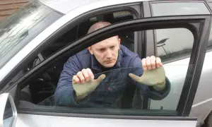 Mężczyzna próbuje podnieść szybę elektryczną w samochodzie, która nie chce się podnieść.