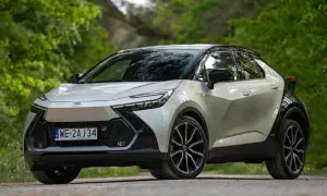 Nowy Toyota C-HR GR Sport w kolorze srebrnym z czarnym dachem, zaparkowany na leśnej drodze. Sprawdź atrakcyjną toyota chr cena!
