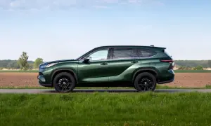 Zielony Toyota Grand Highlander z czarnymi felgami na tle pól i nieba.