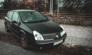 Czarny Renault Vel Satis z miedzianymi felgami stoi przy torach kolejowych.