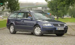 Ciemnoniebieski Volkswagen Passat kombi, model b5, stoi na brukowanym placu.