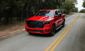 Czerwony Dodge Ram 1500 5.7 Hemi pędzi po krętej drodze wśród drzew.