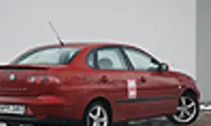 Czerwony Seat Cordoba z naklejką na drzwiach, zaparkowany na zewnątrz.
