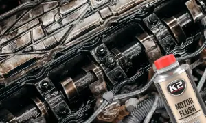 Zabrudzony silnik samochodowy i butelka K2 Motor Flush – dobra płukanka do silnika, która przywróci mu czystość i sprawność.