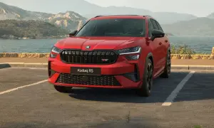 Czerwony Skoda Kodiaq RS zaparkowany nad jeziorem, z górami w tle.