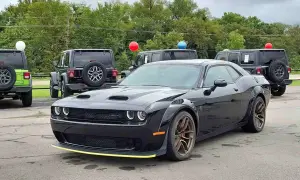 Czarny Dodge Challenger SRT z żółtym akcentem na zderzaku. Obok inne samochody i balony. Sprawdź dodge challenger cena!