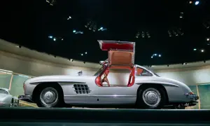 Srebrny Mercedes 300 SL z charakterystycznymi drzwiami otwieranymi do góry, prezentowany w muzeum.
