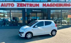 Biały Nissan Pixo zaparkowany przed salonem Auto Zentrum Magdeburg.