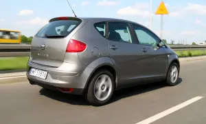 Szary Seat Altea XL jedzie po autostradzie. W tle widać żółty autobus i żółty znak ostrzegawczy.