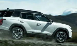 Biały SUV torres auto pokonuje wyboistą drogę, wzbijając tumany kurzu. W tle górzysty, surowy krajobraz.