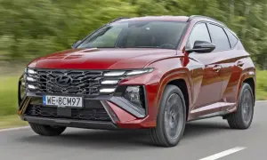 Czerwony Hyundai Tucson z charakterystycznym grillem i światłami LED pędzi po drodze. TCO.