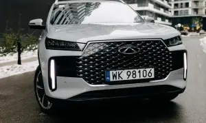 Biały Tiggo 4 z charakterystycznym grillem i pionowymi światłami LED, zaparkowany na mokrej drodze.