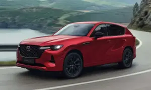 Czerwona Mazda CX-60 3.3 diesel pokonuje zakręt na malowniczej drodze.