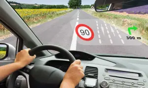 Widok z kabiny samochodu. Na szybie wyświetla się HUD z ograniczeniem prędkości 90, nawigacją i odległością 300 m do skrętu.