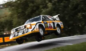 Audi Sport Quattro w akcji, pokonuje nierówność drogi, unosząc się w powietrzu.