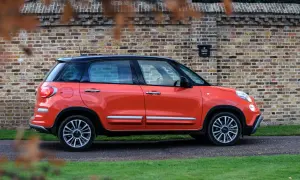 Pomarańczowy Fiat 500 XL z czarnym dachem zaparkowany przy ceglanej ścianie.