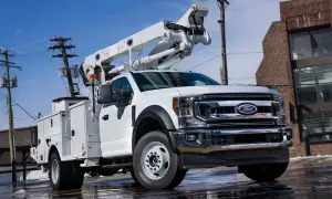 Biały Ford F650 z podnośnikiem koszowym, gotowy do pracy przy liniach energetycznych.