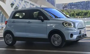 Jasnoniebieski Leapmotor T03 jedzie po drodze, z nowoczesną architekturą w tle.