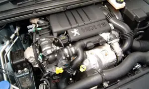 Silnik 1.6 HDI z logo Peugeot. Widoczne elementy układu dolotowego i chłodzenia.