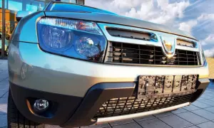Złoty Dacia Duster 1.6 benzyna z bliska, z widocznym grillem i reflektorami.