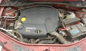 Silnik Renault 1.5 dCi w samochodzie Dacia. Widoczny jest czarny plastikowy dekiel silnika z napisem RENAULT 1.5 dCi, akumulator i elementy układu chłodzenia.