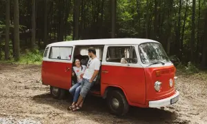 Para zakochanych odpoczywa przy swoim czerwono-białym vw t2 w lesie.