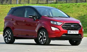 Czerwony Ford EcoSport z czarnym dachem, zaparkowany na tle zielonego zbocza.
