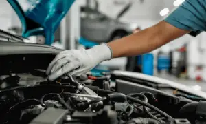 Mechanik w białej rękawiczce sprawdza silnik, szukając objawów zapowietrzonego reduktora LPG.