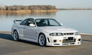 Białe r33 GT-R z siedzeniami Nismo stoi nad jeziorem.