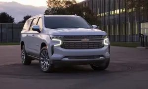 Biały Chevrolet Suburban zaparkowany przed nowoczesnym budynkiem.